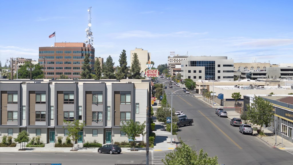 A street view of a city with cars driving on the road and buildings on both sides.